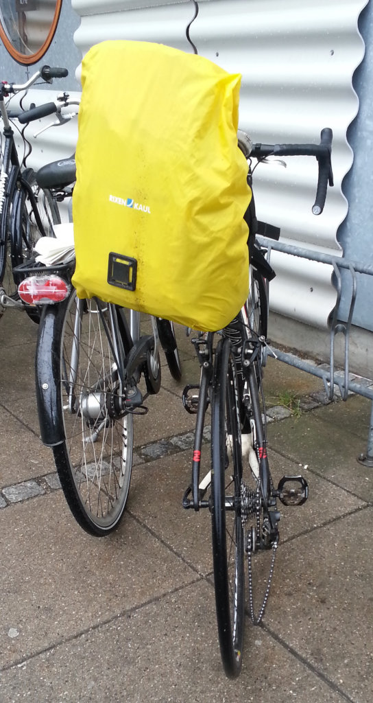 Cyklen med regncover over tasken